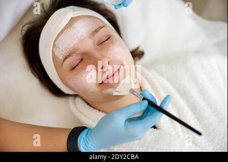 Gros plan de la belle femme brunette appréciant l'application du masque de beauté avec les yeux fermés. Banque D'Images