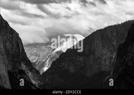 Vue à distance de Half Dome et Cloud Rest couvert de nuages en noir et blanc. Yosemite Valley, parc national de Yosemite, High Sierra, Californie, États-Unis. Banque D'Images