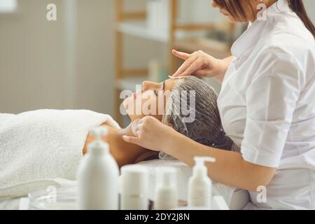 Femme cosmétologue nettoyant le visage des femmes avec des tampons de coton après ou avant la procédure de soin de la peau Banque D'Images