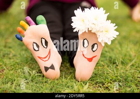 Des images de groom et de mariée adorables juste mariés peint dans des couleurs vives sur les pieds de l'enfant à l'extérieur en été. Penser hors de la boîte Banque D'Images