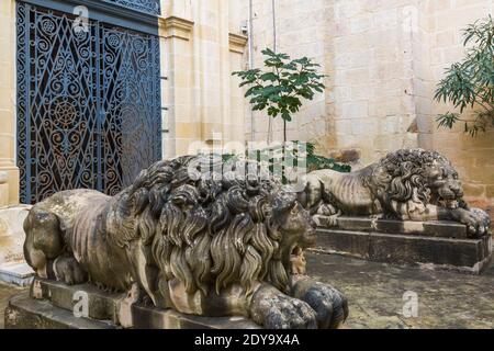 Sculptures de lion de calcaire sculptées et porte d'entrée voûtée avec grils en fer forgé très ornés, jardin du Palais des Grands maîtres, Valette, Malte Banque D'Images