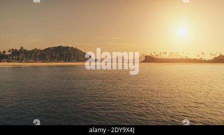 Coucher de soleil sur la mer à l'antenne de plage de sable. Vacances d'été à tropique paradis île avec palmiers au bord de mer. Personne paysage de la nature d'El Nido Islet, Philippines. Tir de drone cinématographique Banque D'Images