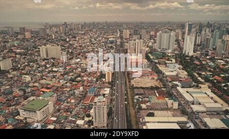 Parking en haut à hauteur des bâtiments élevés, autoroute avec voitures et camions. Route routière du centre-ville dans un paysage urbain urbain avec vue aérienne. Transport local de la capitale philippine, ville de Manille tir de drone Banque D'Images