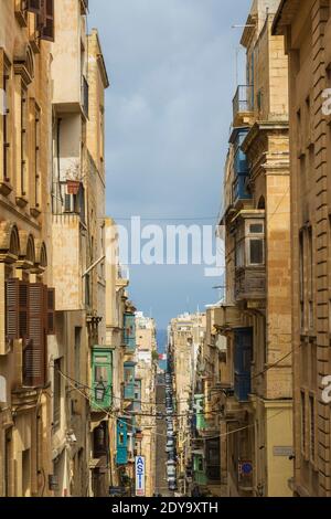 Rue étroite longue et anciens immeubles architecturaux avec balcons maltais, la Valette, Malte Banque D'Images