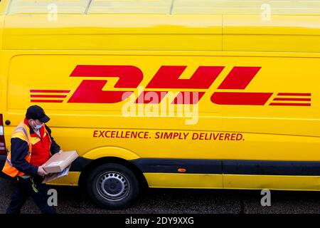 Londres, Royaume-Uni. 23 décembre 2020. Un chauffeur de livraison DHL avec un colis à la main se trouve à côté du minibus DHL à Londres. Crédit : SOPA Images Limited/Alamy Live News Banque D'Images