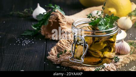 Moules en conserve dans l'huile d'olive et jus de citron avec épices, ail et herbes, table de cuisine en bois noir, foyer sélectif Banque D'Images