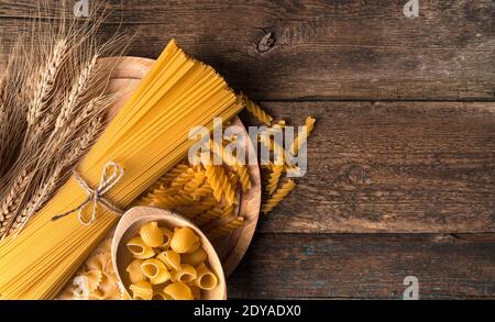 Spaghetti et différents types de pâtes sur fond de bois. Banque D'Images