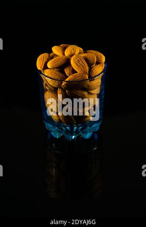 Badam cru riche en protéines empilé dans un verre sur un sombre tableau Banque D'Images