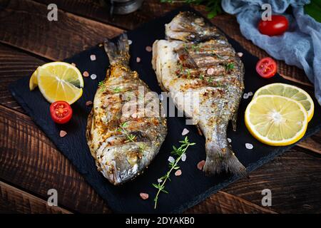 Poisson dorado grillé sur fond de bois. Fruits de mer rôtis aux épices et aux herbes Banque D'Images