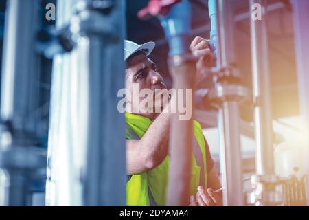 un technicien d'usine répare et vérifie la conduite d'eau haute pression dans la chaufferie de l'usine Banque D'Images