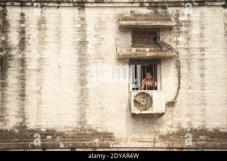 Une jeune fille regarde à travers la fenêtre pendant le confinement de Covid-19 en Inde. Banque D'Images