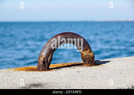 Vieux poteau de bollard d'amarrage en acier sur un quai, mouillage rouillé . Banque D'Images