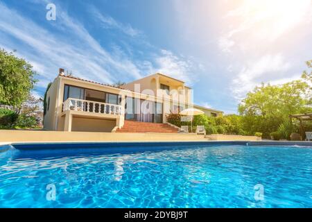 Une piscine de luxe avec de l'eau bleu clair donnant sur le jardin de la villa. À louer aux touristes. Banque D'Images