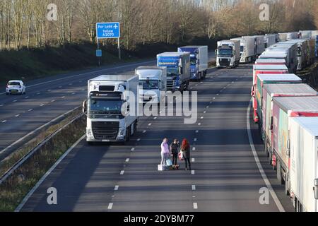 Trois femmes mettent de la nourriture et de l'eau à la disposition des conducteurs sur la M20 près d'Ashford, dans le Kent, où des centaines de voyageurs passent le jour de Noël en attendant de reprendre leur voyage vers le port de Douvres et de l'autre côté de la Manche maintenant que les frontières avec la France ont rouvert. Banque D'Images