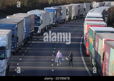 Trois femmes mettent de la nourriture et de l'eau à la disposition des conducteurs sur la M20 près d'Ashford, dans le Kent, où des centaines de voyageurs passent le jour de Noël en attendant de reprendre leur voyage vers le port de Douvres et de l'autre côté de la Manche maintenant que les frontières avec la France ont rouvert. Banque D'Images