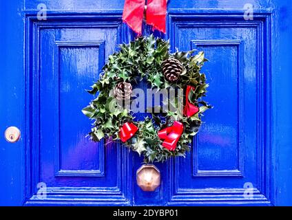 Holly Wreath avec des cônes de pin sur la porte d'entrée bleue, Hertfordshire Royaume-Uni Banque D'Images