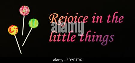 Slogan motivationnel, joie dans les petites choses, sucettes sur fond noir, repos après une journée émotionnelle dure, copie de la photo de bannière d'espace Banque D'Images