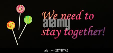 Nous devons rester ensemble, slogan motivationnel dans une période difficile de la vie, pandémie, sucettes sur une photo de fond noir Banque D'Images