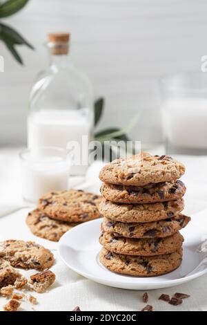 Biscuits au chocolat et lait sur fond de bois blanc. Concept de nourriture douce. Banque D'Images