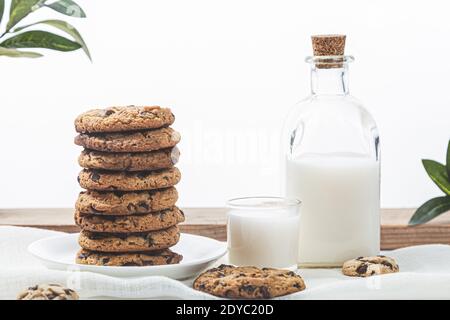 Biscuits au chocolat et lait sur fond de bois blanc. Concept de nourriture douce. Banque D'Images