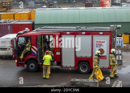 ZUTPHEN, PAYS-BAS - 08 décembre 2020 : voiture et pompiers retournant et entrant dans leur camion rouge sur un chantier de construction après intervention de premiers secours Banque D'Images