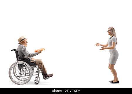 Photo de profil d'un homme âgé dans un fauteuil roulant jouant un jeu avec un disque en plastique avec un jeune femme isolée sur fond blanc Banque D'Images