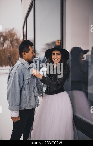 L'homme et la femme hispaniques mexicains en chapeau embrasent en train de rire en marchant. Marié mariée mariage amour couple en hiver dans la neige sur fond de boutique wi Banque D'Images
