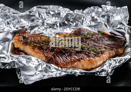 Steak de longe grillé en feuilles. Arrière-plan noir. Vue de dessus. Banque D'Images