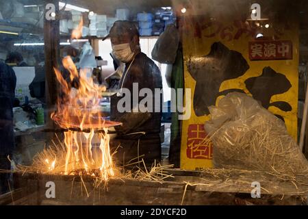 Homme cuisant katsuo no tataki (bonite poêlée) sur une flamme de paille ouverte, Kochi, Japon Banque D'Images