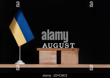 Calendrier en bois d'août avec drapeau ukrainien sur fond noir. Dates en Ukraine en août. Banque D'Images