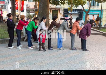 Vietnam Hanoï femmes faisant se donner les autres frotte de dos après des exercices de soirée le long du lac Hoan Kiem. Banque D'Images