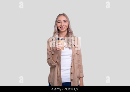 Fille tenant une tasse à café à emporter. Une fille avec une tasse à café à emporter entre les mains. Banque D'Images