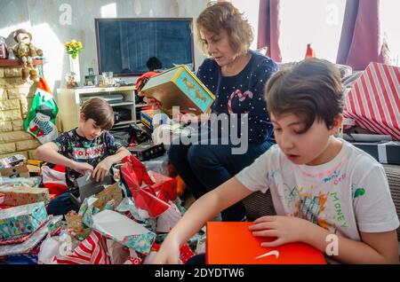 Une famille ouvre des cadeaux de Noël ensemble à la maison le jour de Noël. Banque D'Images