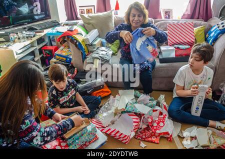 Une famille ouvre des cadeaux de Noël ensemble à la maison le jour de Noël. Banque D'Images