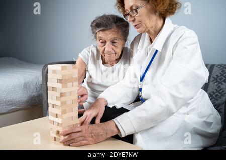 La démence thérapie de manière ludique, l'entraînement des doigts et les compétences fines de moteur, construire des blocs de bois dans la tour, jouant Jenga. Femme âgée de 90 ans et Banque D'Images