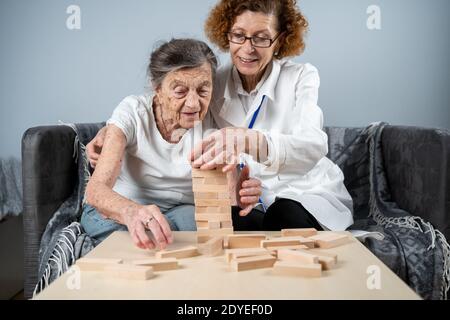 La démence thérapie de manière ludique, l'entraînement des doigts et les compétences fines de moteur, construire des blocs de bois dans la tour, jouant Jenga. Femme âgée de 90 ans et Banque D'Images