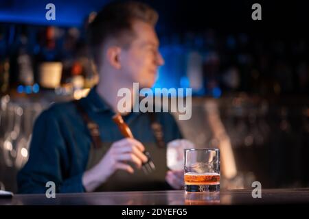 le barman prépare un cocktail traditionnel à l'ancienne avec du whisky et de l'orange Banque D'Images