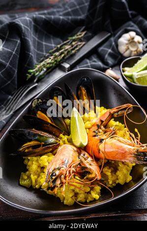 La paella espagnole de fruits de mer aux crevettes, crevettes, poulpes et moules. Arrière-plan en bois noir. Vue de dessus Banque D'Images