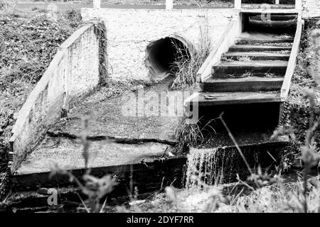 Un trou d'égout expulse l'eau vers la rivière à la campagne village Banque D'Images