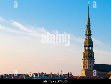 Symbole de Riga, vieille horloge sur la tour médiévale de l'église de Saint-Pierre, parmi les toits anciens bâtiments à l'architecture européenne Banque D'Images