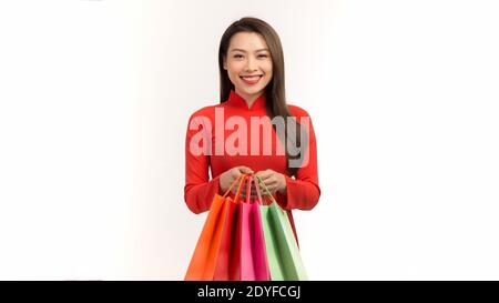 Jeune fille gaie portant une tenue traditionnelle vietnamienne portant des boutiques colorées sacs Banque D'Images