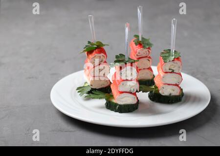 Le crabe croque des canapés avec du fromage, de l'ail et du concombre sur fond gris. Délicieux en-cas festifs. Banque D'Images