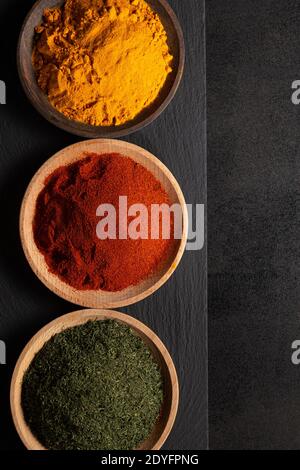 Différentes épices sur fond noir, vue de dessus, avec espace de copie. Condiments de cuisine concept. Banque D'Images
