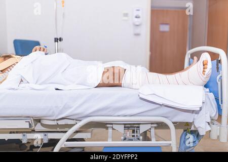 Patient allongé dans le lit d'hôpital avec une jambe cassée. Concept d'hospitalisation et de soins médicaux. Banque D'Images