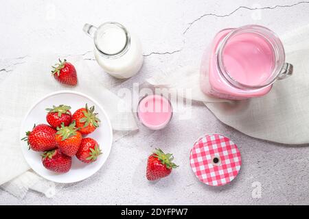 Lait de fraise Pitcher à shake, fraises et lait sur fond blanc. Vue de dessus. Banque D'Images