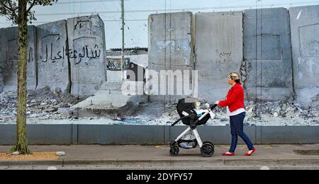 Photo du dossier datée du 30/09/19 d'une femme qui passe devant un mur de la paix de Belfast et qui expose des photos du photographe allemand Kai Wiedenhofer des murs frontaliers du monde, devant le Brexit. Le Royaume-Uni et l'UE sont parvenus à un accord commercial post-Brexit. Banque D'Images