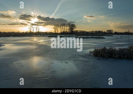 Un lac gelé avec roseaux dans l'est de la Pologne au coucher du soleil, vue en hiver Banque D'Images