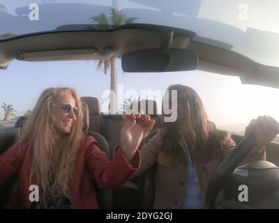 Un jeune couple heureux qui s'amuse lors d'un voyage en voiture décapotable. Amoureux romantiques appréciant le temps ensemble conduite automobile cabriolet dans des vacances de luxe à Banque D'Images