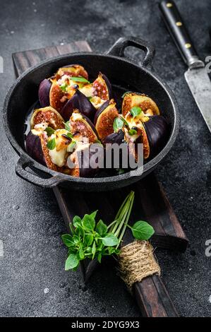Figues au four avec fromage à la crème, miel et noix. Arrière-plan noir. Vue de dessus Banque D'Images