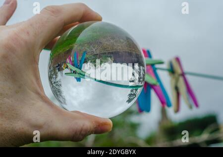 Se fixe sur une ligne de lavage dans un jardin vu à l'envers dans une boule de cristal de verre qui agit comme une lentille et provoque la réfraction. Banque D'Images